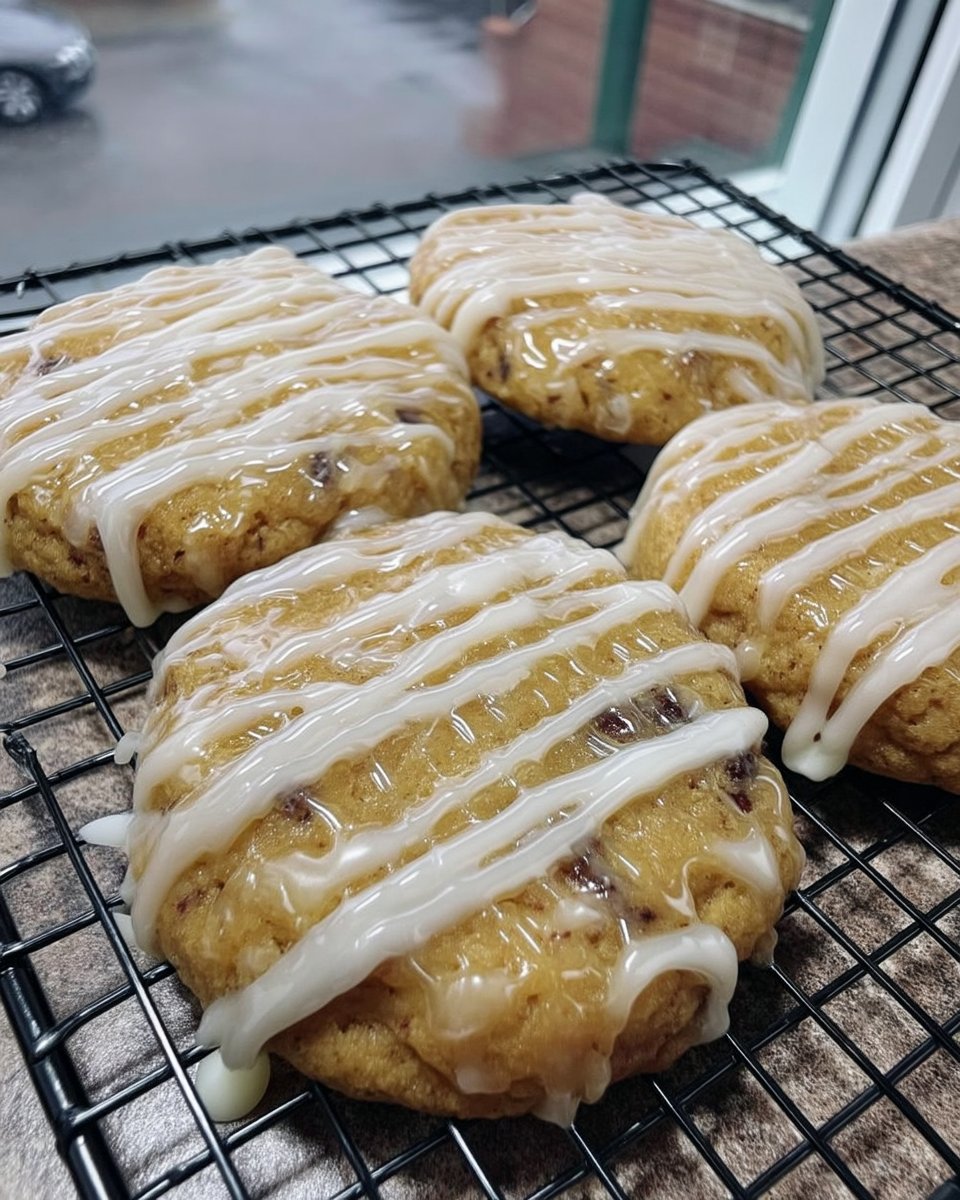 A dozen lemon cookies with a white glaze setting on a wire cooling rack