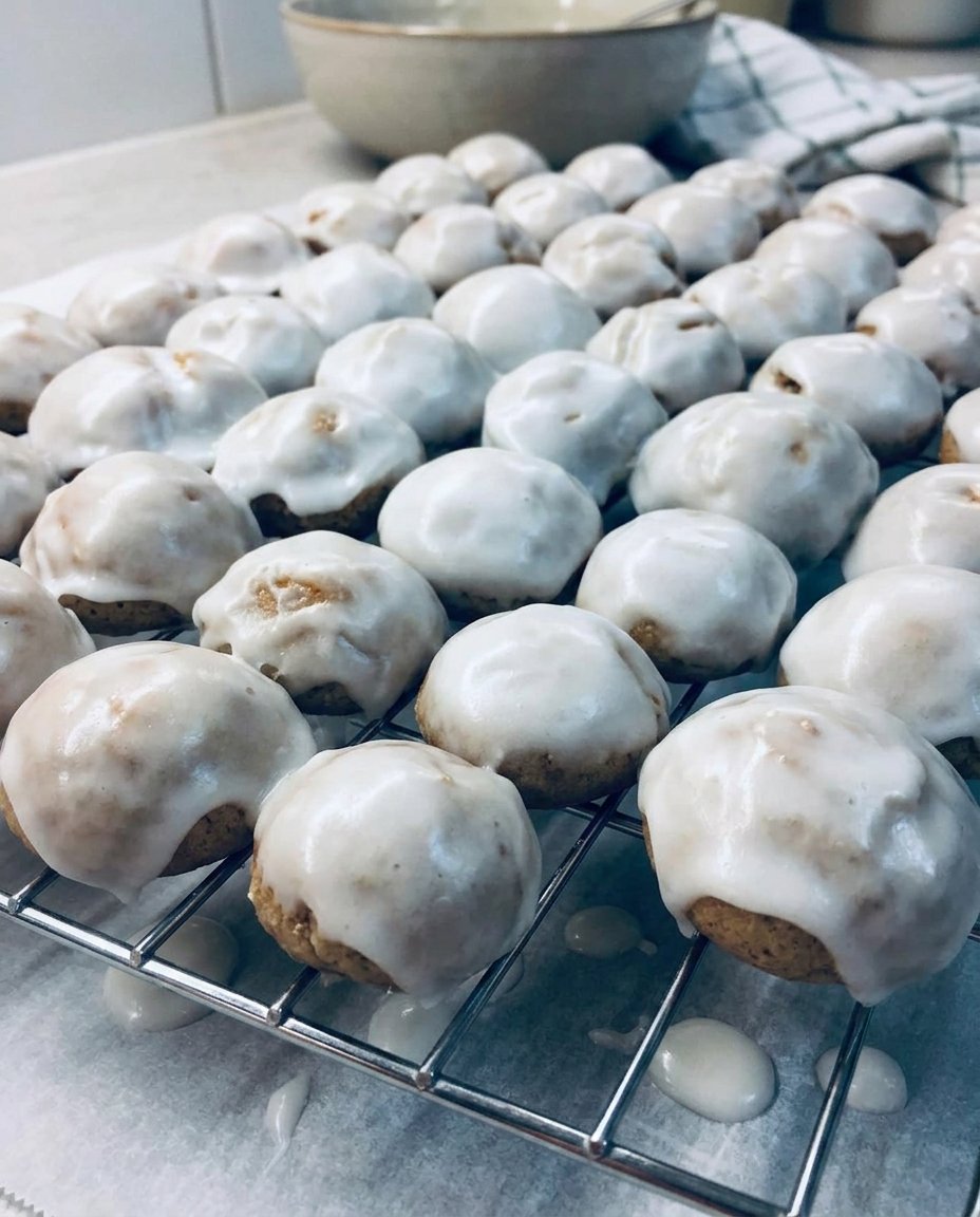 Traditional pfeffernusse spice cookies with a white glaze on a rustic wooden table