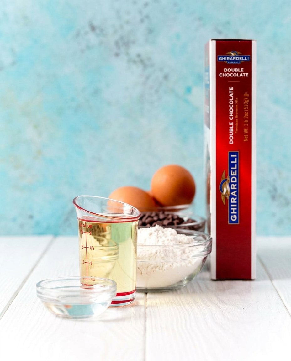 Ingredients for brownie mix cookies including boxed mix, eggs, flour, and walnuts